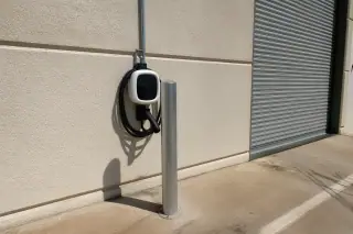 Industrial EV charging station mounted on a metal post against a stucco wall in Phoenix, AZ.