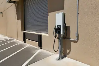 Industrial EV charging station mounted on a metal post near a steel roll-up door in Phoenix, AZ.