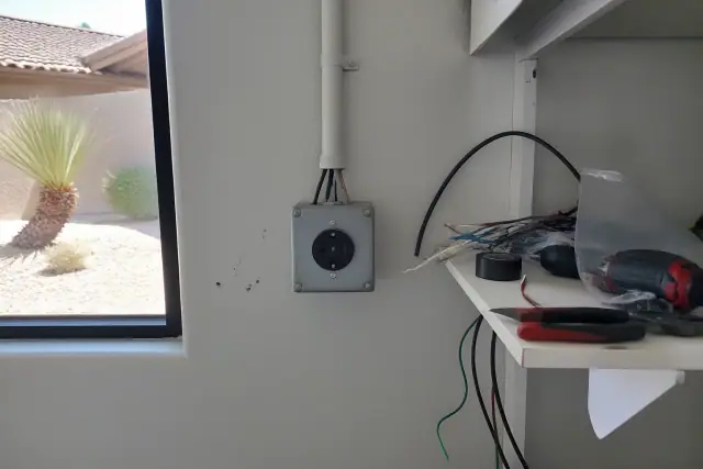 NEMA 14-50 outlet installation in a Phoenix, AZ utility room with tools and desert xeriscaping visible through a window.