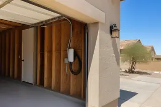 Wall-mounted EV charger with conduit installed on exposed timber garage studs in Phoenix, AZ.