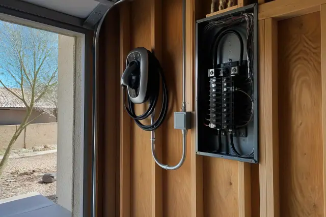 Wall-mounted EV charger and electrical panel installed in a garage in Phoenix, AZ.