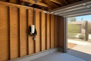 Tesla Wall Connector mounted on exposed timber garage studs in Phoenix, AZ.
