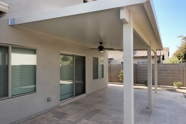 Attached patio cover installed over travertine pavers at a home in Gilbert, AZ.