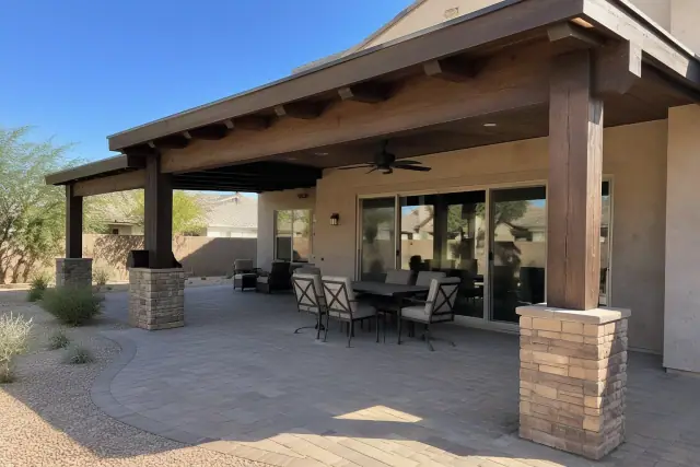 Attached ramada and patio cover with heavy timber posts over stone pavers in Gilbert, AZ.