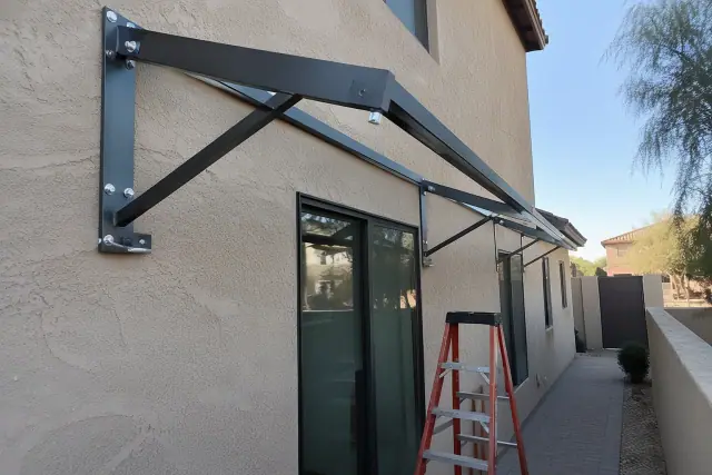Contractor repairing a metal awning frame and hardware on a stucco wall in Gilbert, AZ.