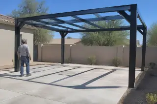 Service professional inspecting a completed metal carport skeleton over a paved parking slot in Gilbert, AZ.