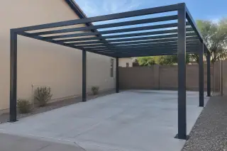 Metal structural skeleton of a carport over a paved parking slot in Gilbert, AZ.