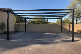 Freestanding metal carport skeleton over a paved vehicle parking slot in Gilbert, AZ.
