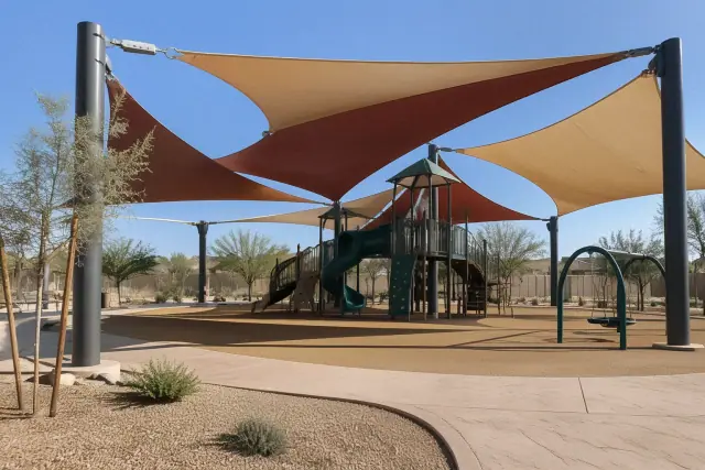 Multi-sail canopy over a commercial playground in Gilbert, AZ, featuring tensioned fabric and steel columns.