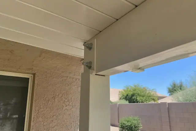Close-up of heavy-duty patio cover fasteners and roof attachment on a stucco wall in Gilbert, AZ.
