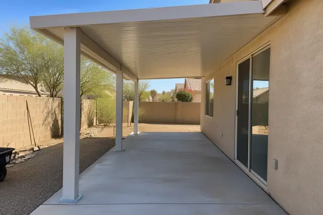 Patio cover installation with solid insulated roof and aluminum posts on a concrete slab in Mesa, AZ.