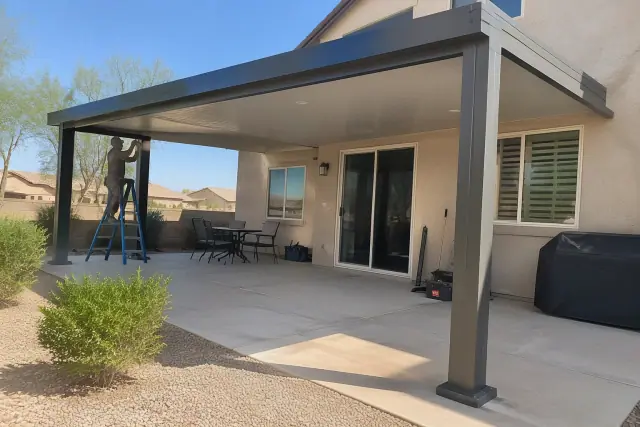Patio cover installation in progress at a Gilbert, AZ home backyard with a louvered roof and concrete slab.