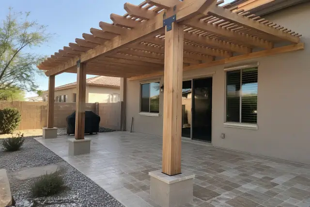 Pergola installation with timber rafters over travertine pavers and stucco wall in Gilbert, AZ.