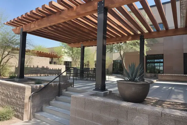 Pergola installation with wood rafters and metal brackets in a split-level commercial courtyard in Gilbert, AZ.