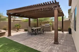 Freestanding wood rafter pergola over a paver patio in a backyard in Gilbert, AZ.