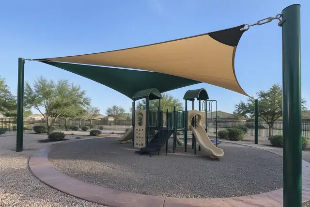 Playground shade sail installation with steel uprights and concrete curbing in Gilbert, AZ.
