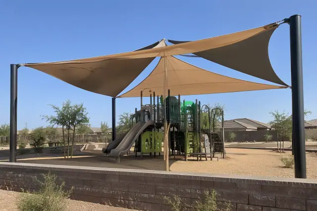 Multi-sail shade canopy installed over a modern playground with steel columns in Queen Creek, AZ.