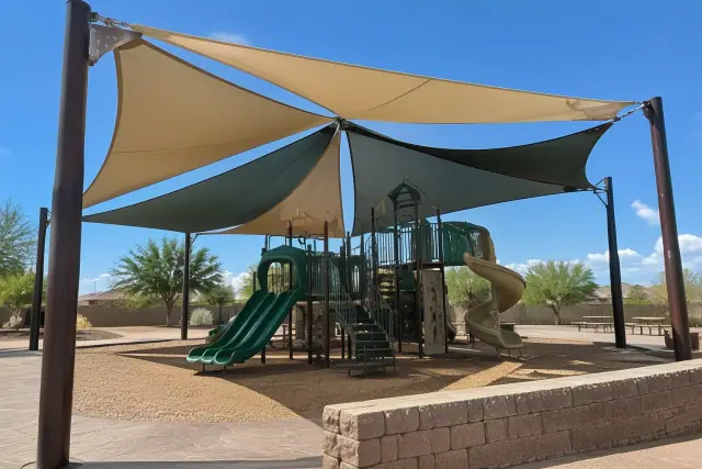 Multi-sail playground shade structure with tensioned fabric bolted to steel columns in Gilbert, AZ.