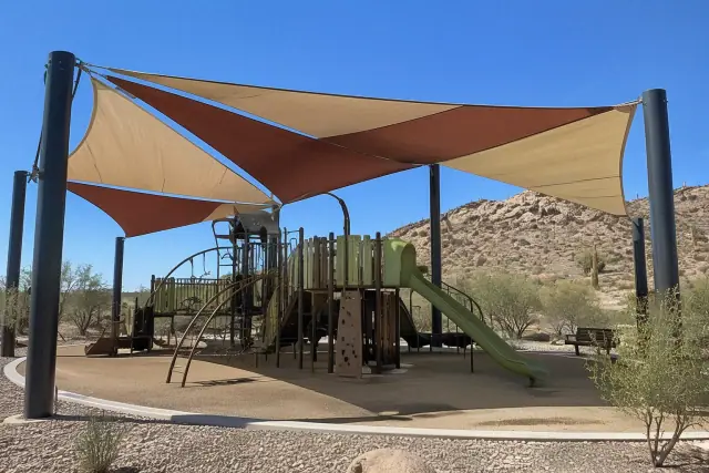 Multi-sail curved hip canopy shade structure installed over a playground in Fountain Hills, AZ.