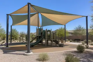 Multi-sail curved hip canopy and steel columns over a playground in Gilbert, AZ.