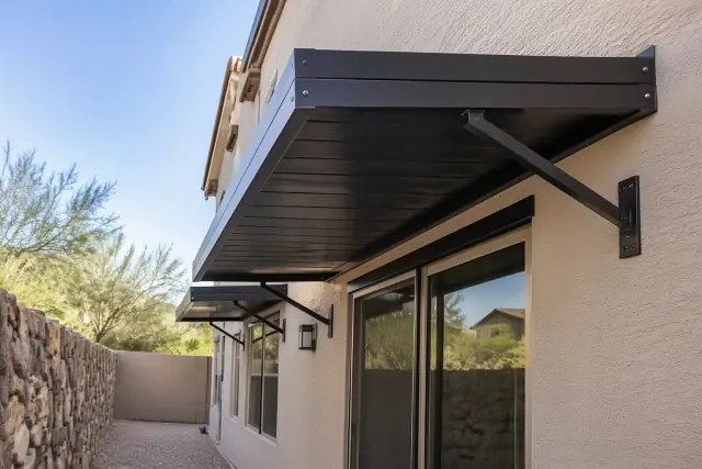 Powder-coated aluminum awnings on a stucco wall in Gilbert, AZ, showing brackets and fasteners.