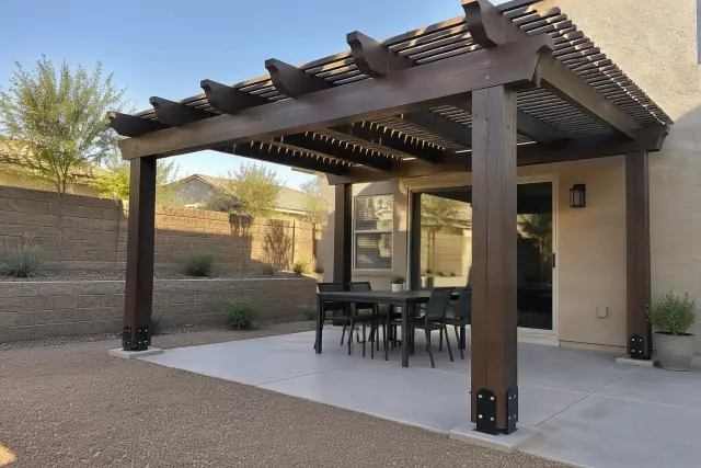 Pergola installation in Gilbert, AZ featuring hand-notched rafter tails and post brackets over a retaining wall.