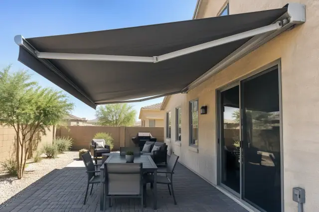 Motorized retractable shade installed on a stucco home over a paver patio in Gilbert, AZ.