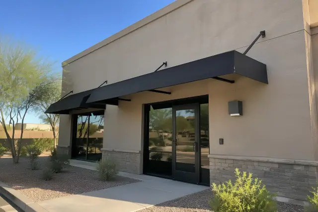 Storefront awnings with mounting brackets above a building entry in Gilbert, AZ.