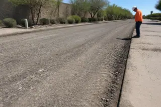 Technician checking the edge of a milled asphalt surface with desert landscaping in Goodyear, AZ.
