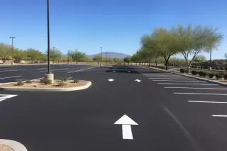 Newly paved parking lot with white stall lines and directional arrows in the bright sunlight of Goodyear, AZ.