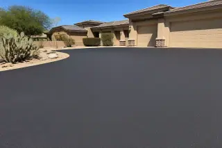 Vibratory roller smoothing fresh asphalt in front of desert landscaping and prickly pear cactus in Goodyear, AZ.