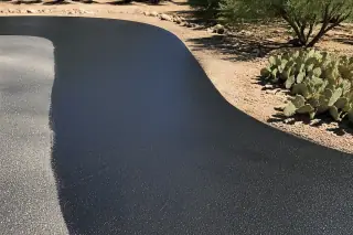 Fresh black sealcoat applied to asphalt with prickly pear cactus in the background in Goodyear, AZ.