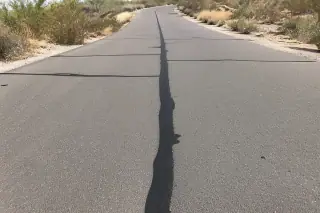 Linear crack sealant applied to an asphalt surface surrounded by desert vegetation in Goodyear, AZ.