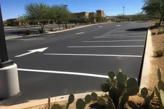 Freshly painted white parking stall lines and directional arrows on an asphalt lot in Goodyear, AZ.
