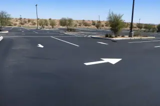 Freshly painted white parking stall lines on a new asphalt lot with desert landscaping in Goodyear, AZ.