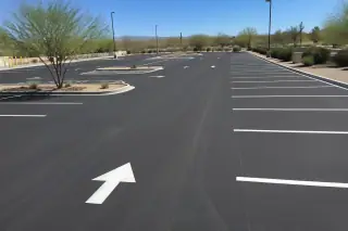 Bright white stall lines and directional arrows on a paved parking lot with desert scrub in Goodyear, AZ.