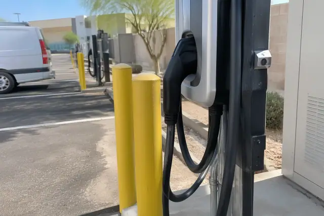 EV charger repair and troubleshooting in an asphalt parking bay in Mesa, AZ.