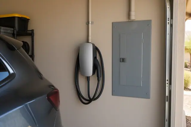 EV charger mounted beside a garage electrical panel in Mesa, AZ.