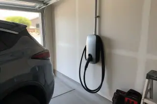 Wall-mounted EV charger and electrical conduit on a drywalled interior garage wall in Mesa, AZ.