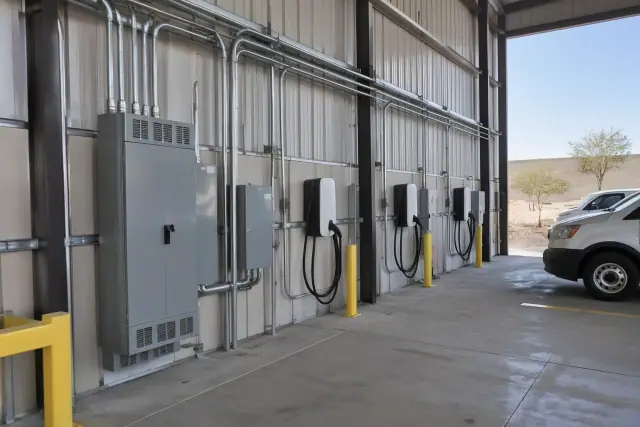 Fleet EV charging station installation with heavy-duty metal conduits on a warehouse wall in Gilbert, AZ.