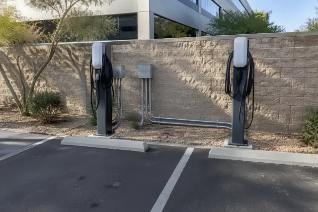 Commercial-office-building exterior in Tempe, AZ showing fleet EV charging station installation with conduit runs and