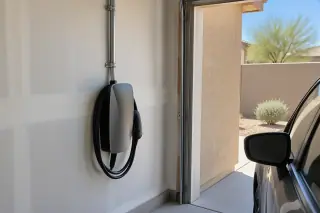 Hardwired EV charger and exposed conduit next to a parked vehicle in Mesa, AZ.