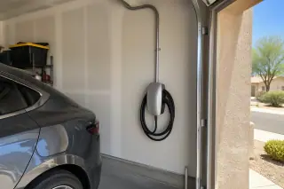 Hardwired wall-mounted EV charger and electrical conduit in a Mesa, AZ garage.