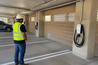 Worker observing a clean EV charger installation near concrete pillars in Mesa, AZ.