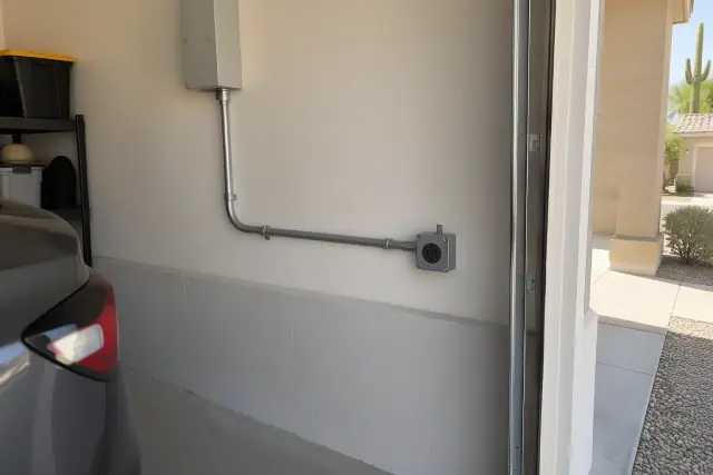 NEMA 14-50 outlet installation with metal conduit on a stucco wall inside a garage in Mesa, AZ.