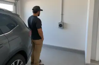 Technician inspecting a NEMA 14-50 outlet above an epoxy garage floor in Mesa, AZ.