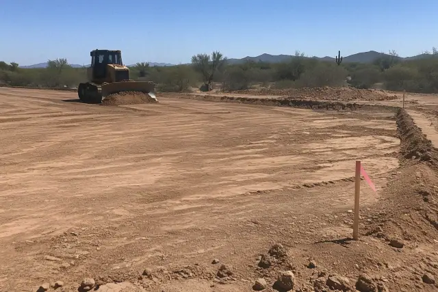 Compacted earthen building pad with grade stakes and laser tracks in San Tan Valley, AZ.