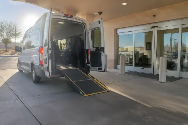 Ambulatory transportation vehicle with extended wheelchair ramp parked at a hospital bay in Mesa, AZ.