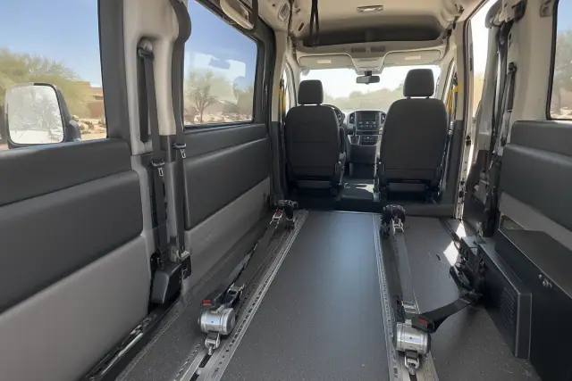 Wheelchair securement straps latched to floor tracks inside a medical transport van in Gilbert, AZ.