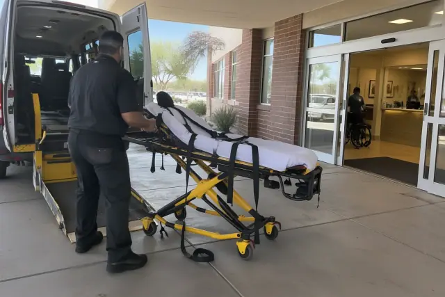 Stretcher transportation service at an outpatient dialysis clinic entrance in Mesa, AZ.